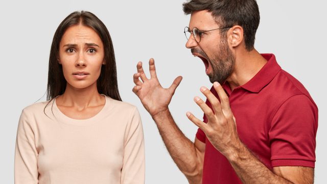 Furious bearded guy screams and gestures angrily, yells at woman, have dispute, pose together over white background. Strict boss being angry with not responsible colleague. What have you done?